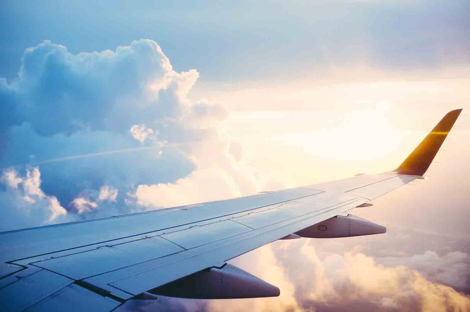 Die Perspektive von einem Platz im Flugzeug hoch oben in den Wolken bei strahlendem Sonnenschein